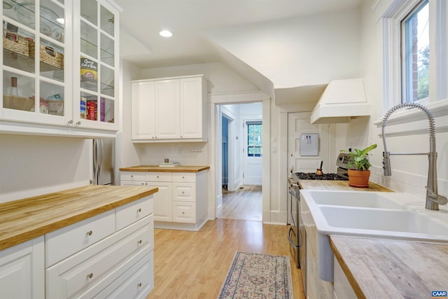 883 Locust Ave, Charlottesville, VA 22902 - kitchen with wood counters, custom exhaust hood, gas range, glass insert cabinets, and light wood-type flooring
