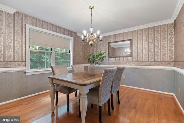  - dining area with wallpapered walls, a chandelier, a wainscoted wall, and wood finished floors