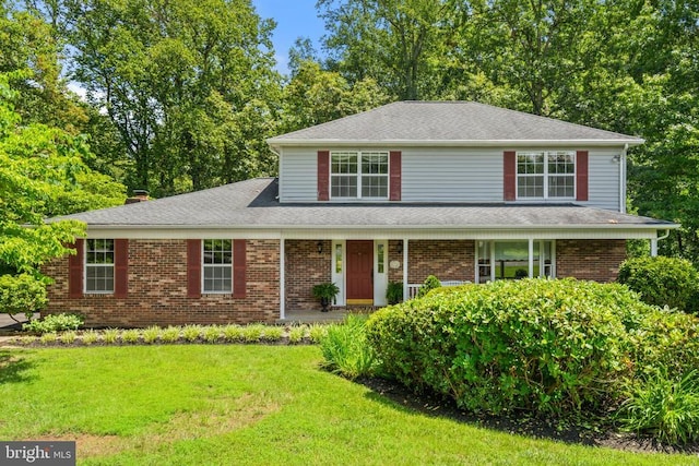  - view of front of home featuring a front lawn, covered porch, brick siding, roof with shingles, and a chimney