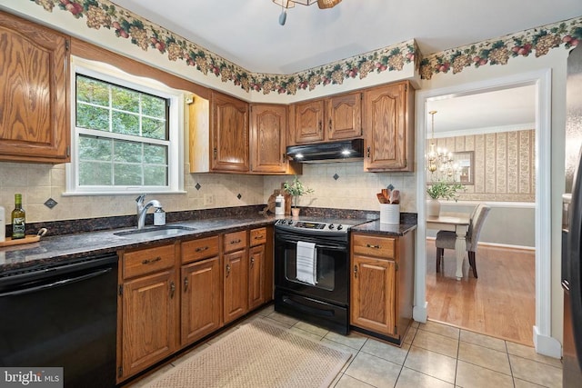  - kitchen with black appliances, under cabinet range hood, a chandelier, and brown cabinetry