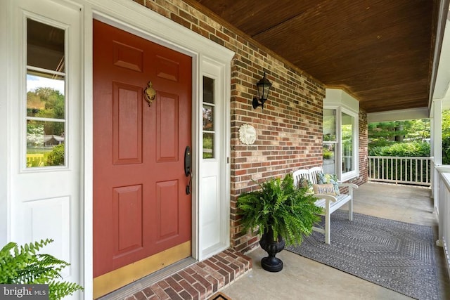  - view of exterior entry featuring covered porch and brick siding