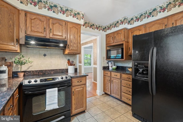  - kitchen featuring black appliances, under cabinet range hood, decorative backsplash, light tile patterned floors, and brown cabinetry