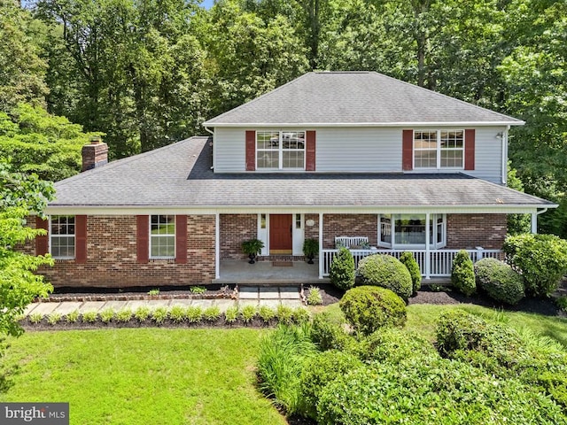  - view of front of home with a porch, a chimney, a front lawn, and roof with shingles