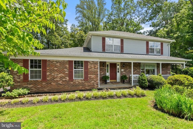 - view of front of home featuring a front yard, covered porch, and brick siding