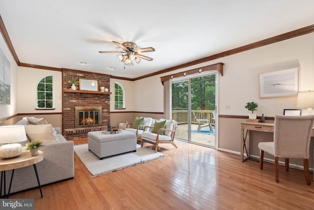  - living room featuring wood finished floors, crown molding, ceiling fan, and a brick fireplace