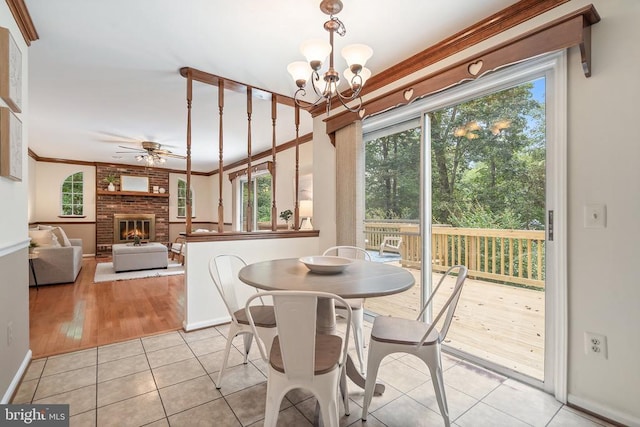  - dining area with plenty of natural light, light tile patterned floors, a ceiling fan, a fireplace, and ornamental molding