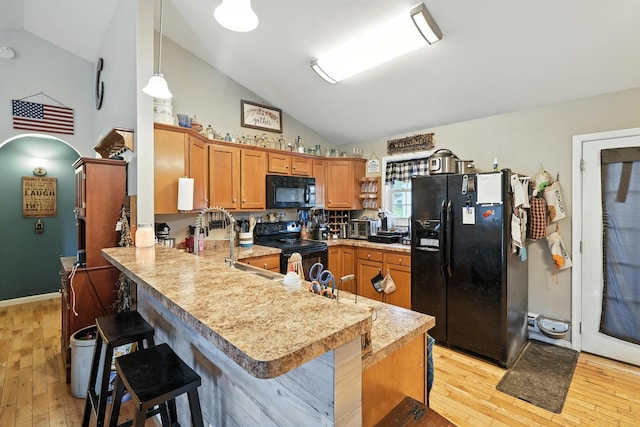 14975 Woodcreek Ln, Timberville, VA 22853 - kitchen featuring black appliances, a peninsula, light countertops, light wood finished floors, and a breakfast bar area
