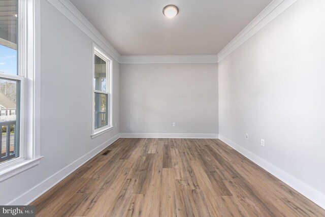 spare room featuring crown molding, wood finished floors, and baseboards