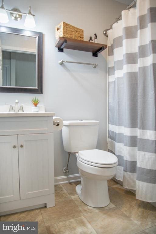 full bathroom with toilet, vanity, baseboards, and curtained shower