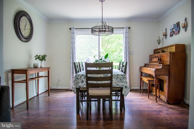 dining area with dark wood-type flooring, crown molding, a chandelier, and baseboards