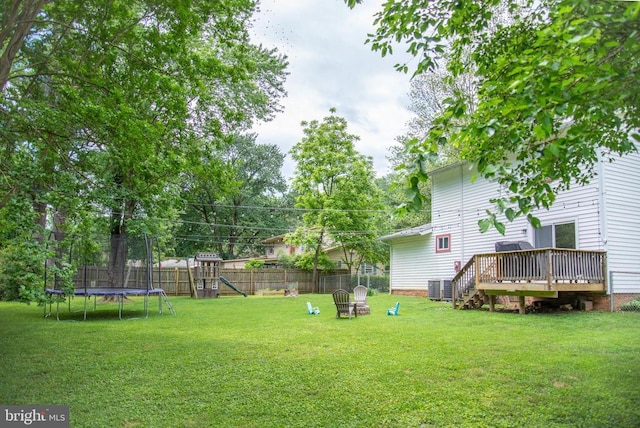 view of yard with a trampoline, a playground, a wooden deck, and central air condition unit