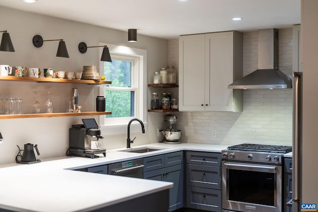 kitchen with a sink, open shelves, wall chimney exhaust hood, stainless steel gas range oven, and backsplash