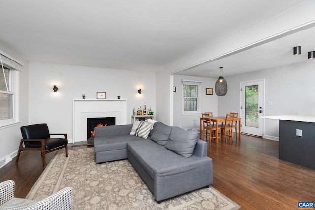 living area featuring baseboards, a brick fireplace, and wood finished floors