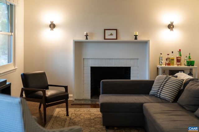 living room featuring plenty of natural light, wood finished floors, and a brick fireplace