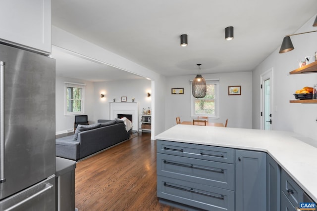 kitchen featuring freestanding refrigerator, a wealth of natural light, dark wood-type flooring, and a peninsula