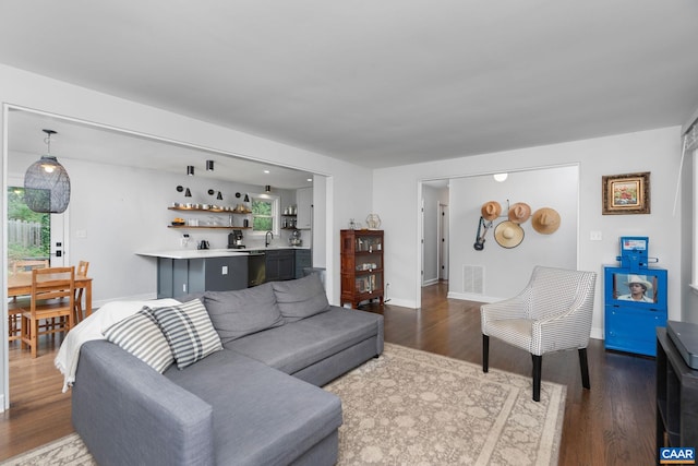 living area with baseboards, dark wood-style flooring, visible vents, and indoor bar