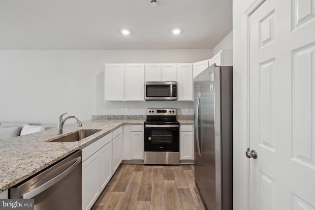 226 Baker Dr, Luray, VA 22835 - kitchen with appliances with stainless steel finishes, a sink, light wood finished floors, light stone counters, and white cabinetry