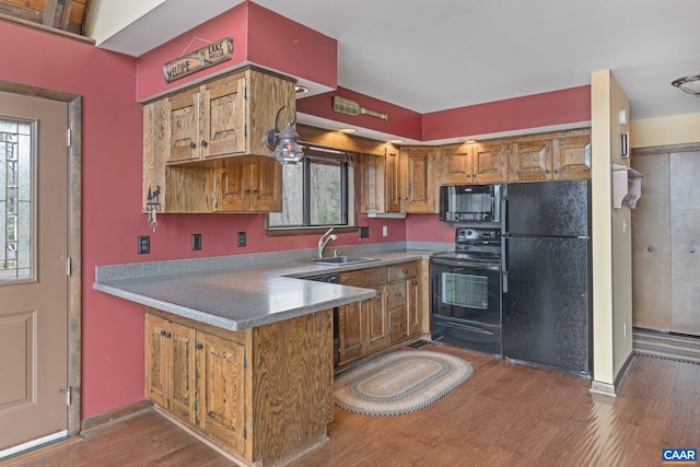 19 Hawks Pl, Palmyra, VA 22963 - kitchen featuring a peninsula, wood finished floors, a sink, brown cabinetry, and black appliances