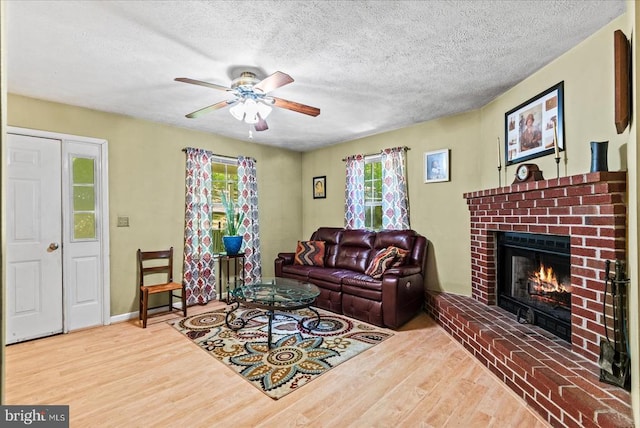 54 Courthouse Mountain Rd, Madison, VA 22727 - living room with wood finished floors, a textured ceiling, a brick fireplace, a ceiling fan, and baseboards