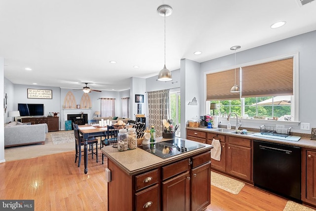  - kitchen featuring black appliances, a ceiling fan, a sink, a fireplace, and light wood-style floors