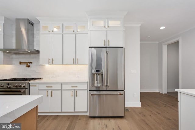 8630 Rosni Way, Fredericksburg, VA 22407 - kitchen with premium appliances, wall chimney range hood, light wood finished floors, decorative backsplash, and crown molding