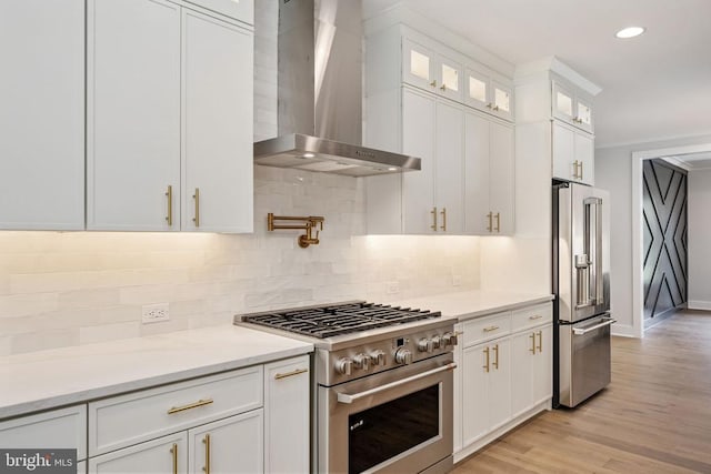 8630 Rosni Way, Fredericksburg, VA 22407 - kitchen with high quality appliances, wall chimney range hood, white cabinetry, backsplash, and light wood-style flooring