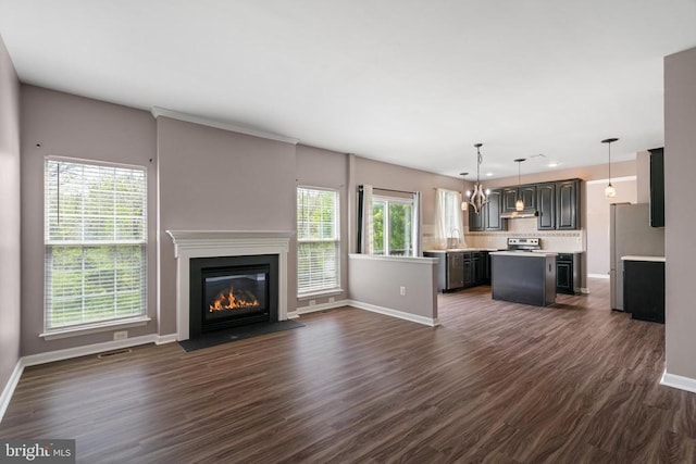 unfurnished living room with baseboards, dark wood-type flooring, a fireplace with flush hearth, a chandelier, and recessed lighting