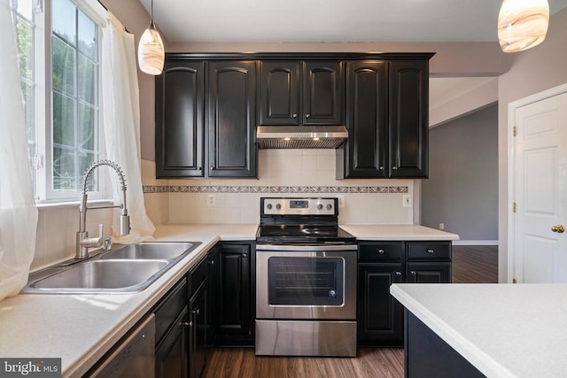 kitchen featuring stainless steel appliances, under cabinet range hood, a sink, and decorative backsplash