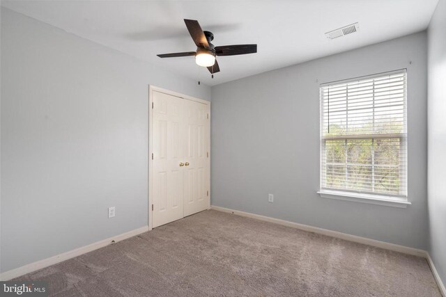 unfurnished bedroom with carpet, baseboards, a closet, and a ceiling fan