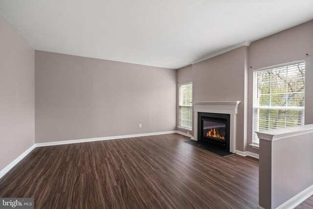 unfurnished living room featuring dark wood-style flooring, a fireplace with flush hearth, and baseboards