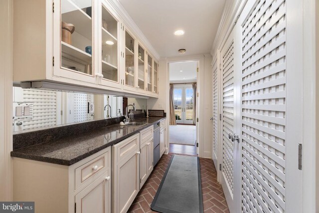  - kitchen with stainless steel dishwasher, brick floors, glass insert cabinets, dark stone countertops, and recessed lighting
