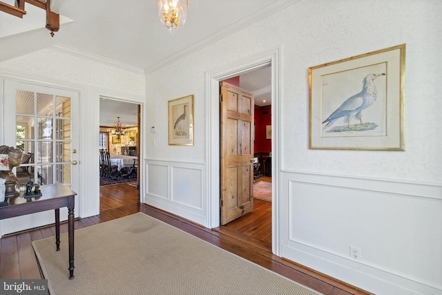  - hallway with a chandelier, hardwood / wood-style flooring, ornamental molding, and wainscoting