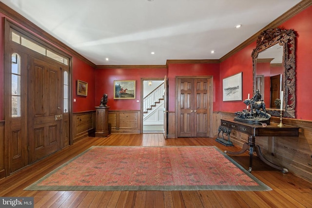  - entrance foyer with hardwood / wood-style flooring, a wainscoted wall, crown molding, stairs, and recessed lighting