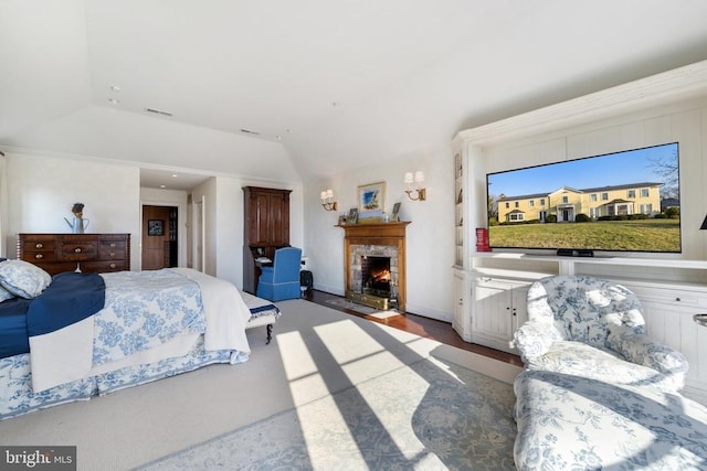  - bedroom featuring a fireplace with flush hearth, vaulted ceiling, and wood finished floors