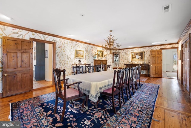  - dining area featuring wallpapered walls, crown molding, hardwood / wood-style flooring, a chandelier, and baseboards