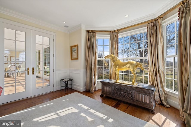 - living area featuring french doors, healthy amount of natural light, hardwood / wood-style floors, ornamental molding, and a wainscoted wall