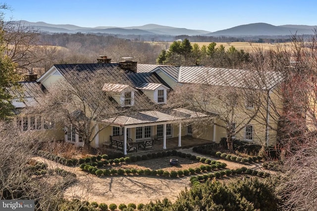 - view of front of home with a standing seam roof, a chimney, a mountain view, a metal roof, and a patio