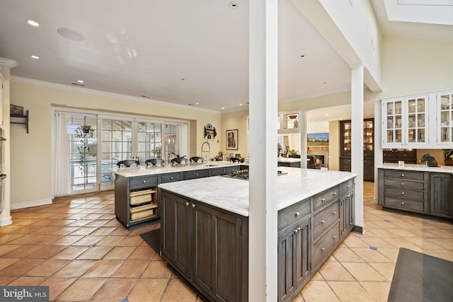  - kitchen with a center island, ornamental molding, recessed lighting, glass insert cabinets, and stainless steel gas stovetop