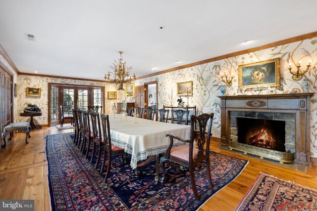  - dining area with wallpapered walls, ornamental molding, hardwood / wood-style flooring, french doors, and a chandelier