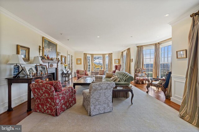  - living room featuring built in shelves, stairs, wood finished floors, crown molding, and a wainscoted wall