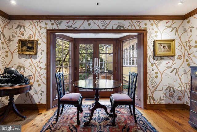  - dining space with wallpapered walls, light wood finished floors, crown molding, and french doors