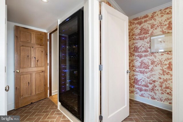  - hallway with brick floors, wallpapered walls, beverage cooler, and crown molding