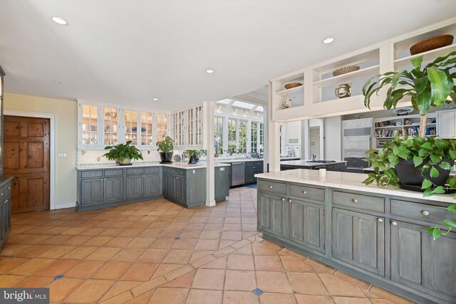  - kitchen featuring gray cabinetry, stainless steel appliances, light countertops, glass insert cabinets, and recessed lighting
