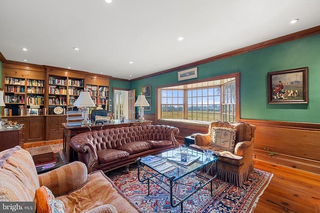  - living area with wainscoting, wood finished floors, recessed lighting, crown molding, and built in features