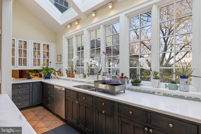  - kitchen featuring dishwasher, a skylight, light tile patterned floors, light countertops, and vaulted ceiling