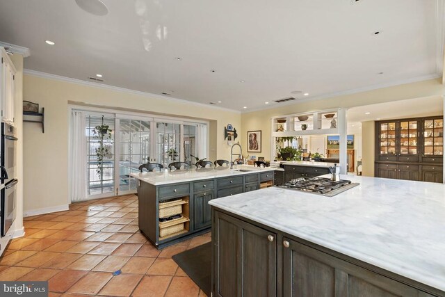  - kitchen featuring stainless steel gas stovetop, ornamental molding, recessed lighting, a center island with sink, and light tile patterned floors