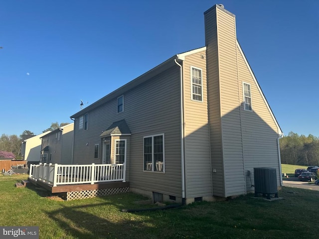 back of property featuring a wooden deck, a lawn, a chimney, and central AC