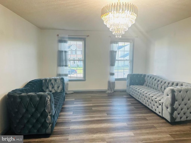 living area featuring baseboards, wood finished floors, a chandelier, and a healthy amount of sunlight