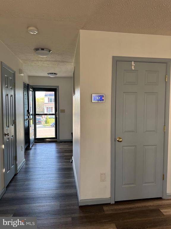 hall with baseboards, a textured ceiling, and dark wood finished floors