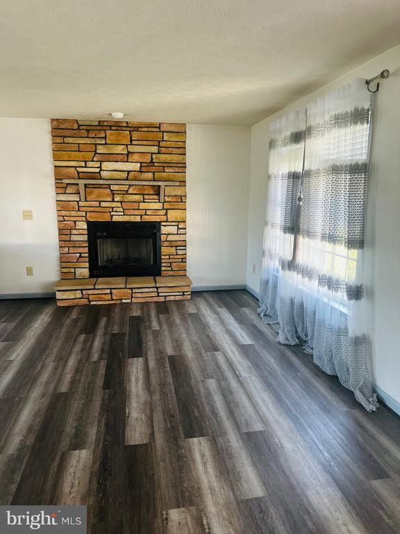 unfurnished living room with baseboards, wood finished floors, and a fireplace